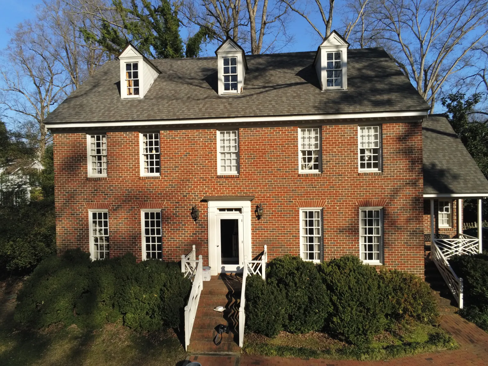 Brick colonial home in mainland Eastern North Carolina with a newly installed asphalt shingle roof and dormers