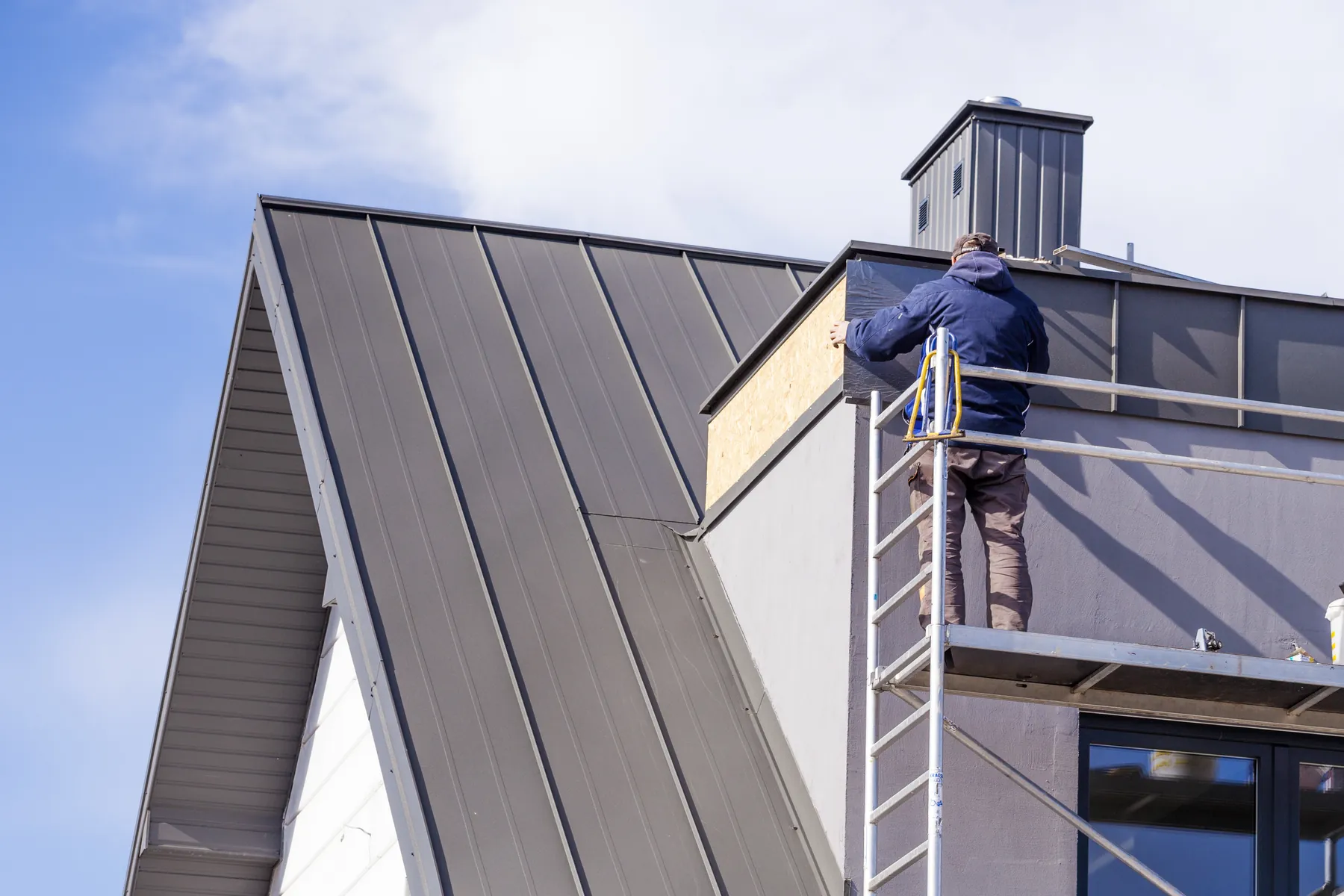 Standing-seam metal roof being installed on a steep-pitch home, a salt-tough rebuild option for the Outer Banks